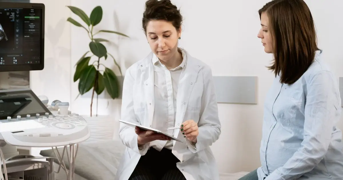 Doctor talking with a pregnant woman next to an ultrasound machine